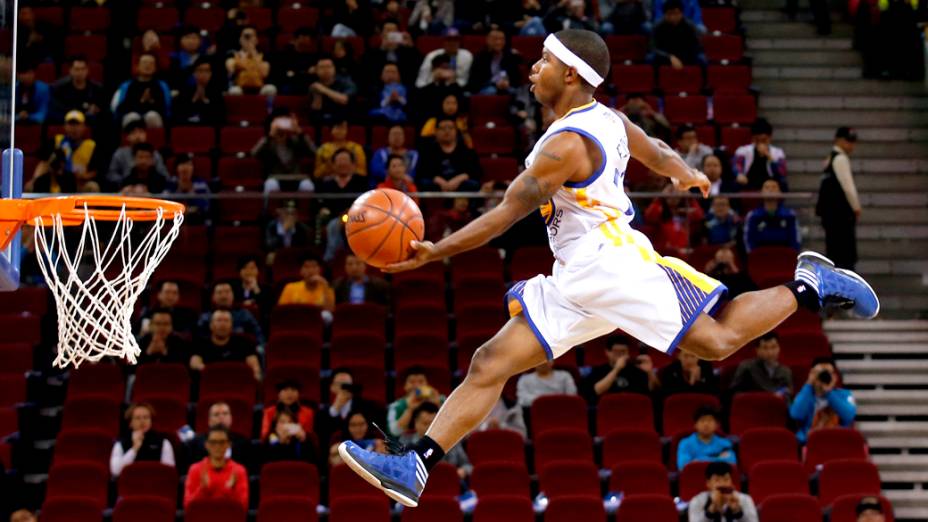 Jogador da equipe de acrobacias do Golden State Warriors, usa cama elástica para dar uma enterrada durante exibição antes da partida contra o Los Angeles Lakers em Pequim, na China