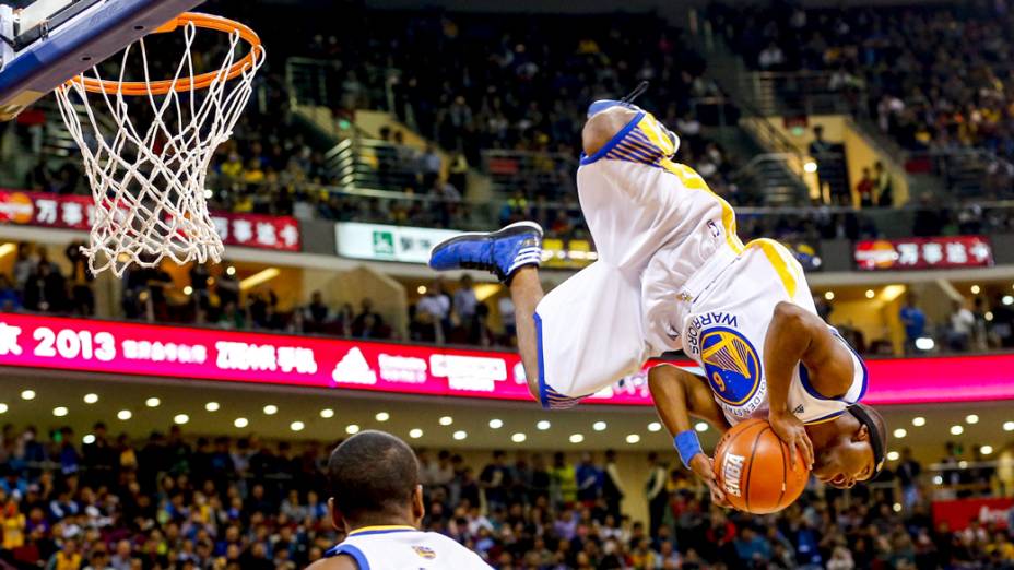 Jogador da equipe de acrobacias do Golden State Warriors, usa cama elástica para dar uma enterrada durante exibição antes da partida contra o Los Angeles Lakers em Pequim, na China