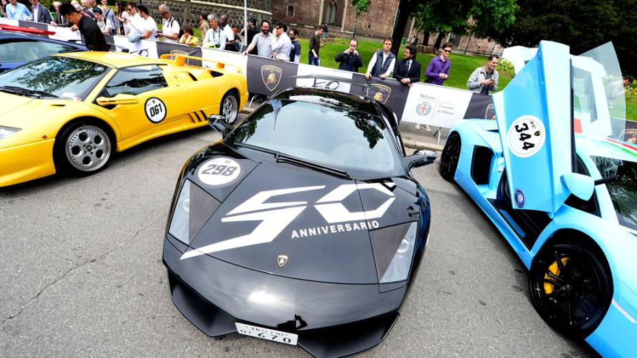 Um Murciélago exibe o logotipo comemorativo aos 50 anos da Lamborghini sobre o capô. Ao lado dele, um Diablo amarelo e um Aventador azul