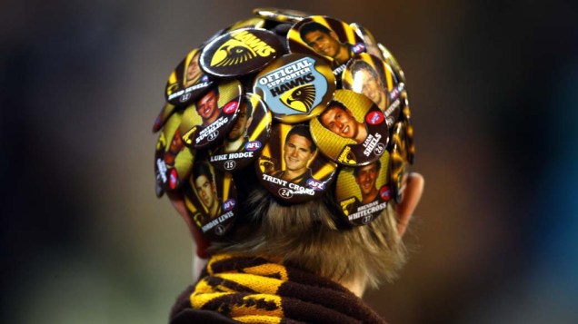 Torcedor usa chapéu com imagens de jogadores durante partida de críquete em Melbourne, Austrália