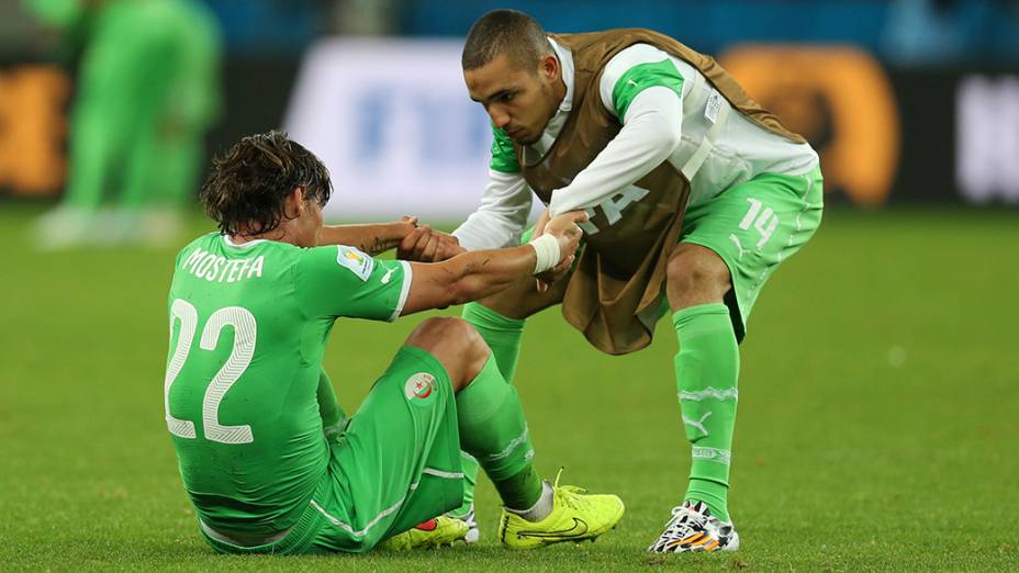 Jogador da Argélia ajuda seu companheiro após a derrota para a Alemanha no Beira-Rio, em Porto Alegre