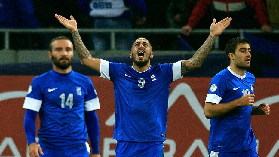 Konstantinos Mitroglou celebra ao lado de companheiros de equipe Socratis Papastathopoulos (R) e Dimitrios Salpingidis, após marcar um gol sobre a Romênia durante repescagem europeia para a Copa do Mundo 2014