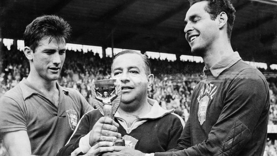 Feola, técnico da seleção, Gylmar e Bellini segurando a Taça Jules Rimet, após a conquista da Copa do Mundo em 1958, na Suécia