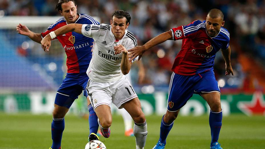 O jogador do Real Madrid Gareth Bale em lance contra Luca Zuffi e Walter Samuel, do Basel, durante partida da Liga dos Campeões, no estádio Santiago Bernabeu, em Madri, na Espanha
