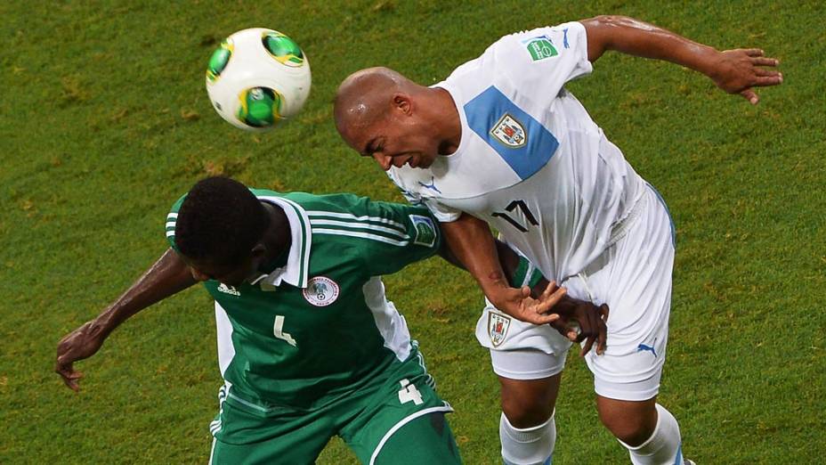 John Ogu e Arevalo Rios disputam bola durante partida entre Nigéria e Uruguai em partida válida pela Copa das Confederações nesta quinta-feira (20), em Salvador