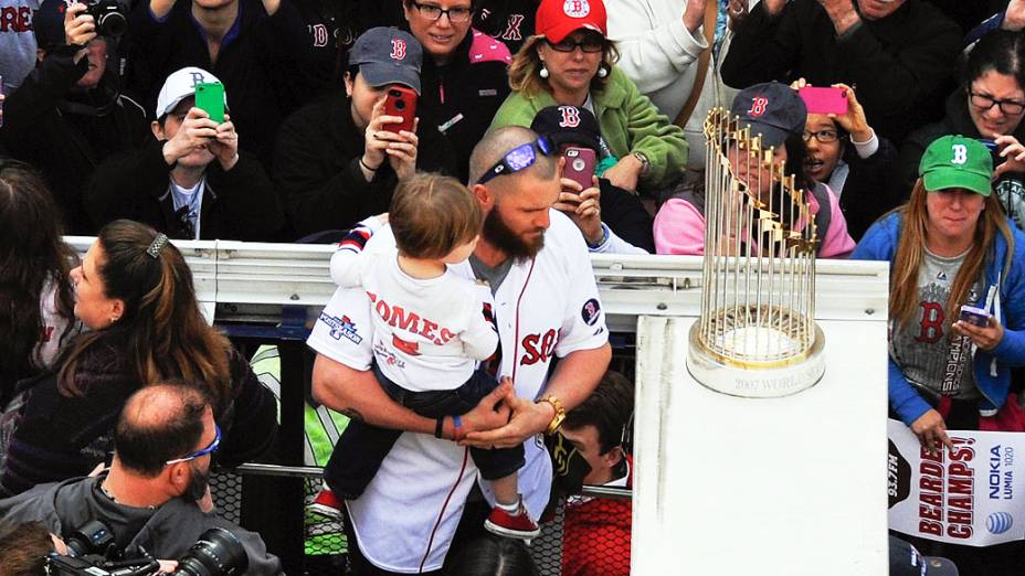 John Gomes segura seu filho na frente do troféu do campeonato World Series durante o desfile para celebração do Red Sox, em Boston