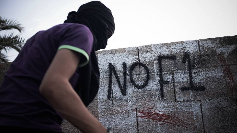 Manifestante mascarado escreve pichações contra o próximo Gp de Fórmula 1 no país à margem de uma manifestação anti-regime, em apoio de ativistas políticos detidos na prisão de Jid Ali, nordeste da Isa Town, no Bahrein