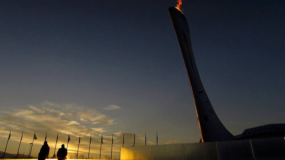 Agentes de segurança, passam pela pira olímpica durante o nascer do sol no Parque Olímpico de Sochi