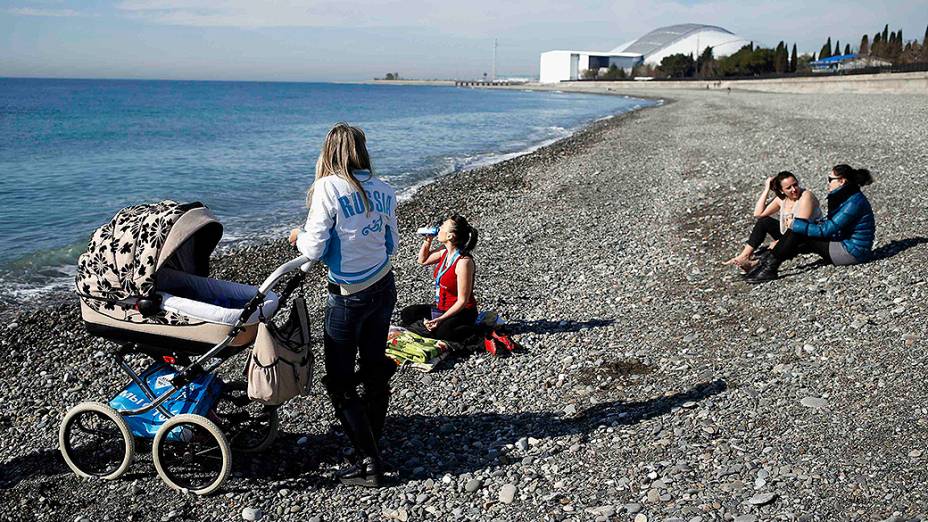 Moradores aproveitam o bom tempo para ir à praia, no Mar Negro, nas proximidades do Parque Olímpico em Sochi, durante os Jogos de Inverno