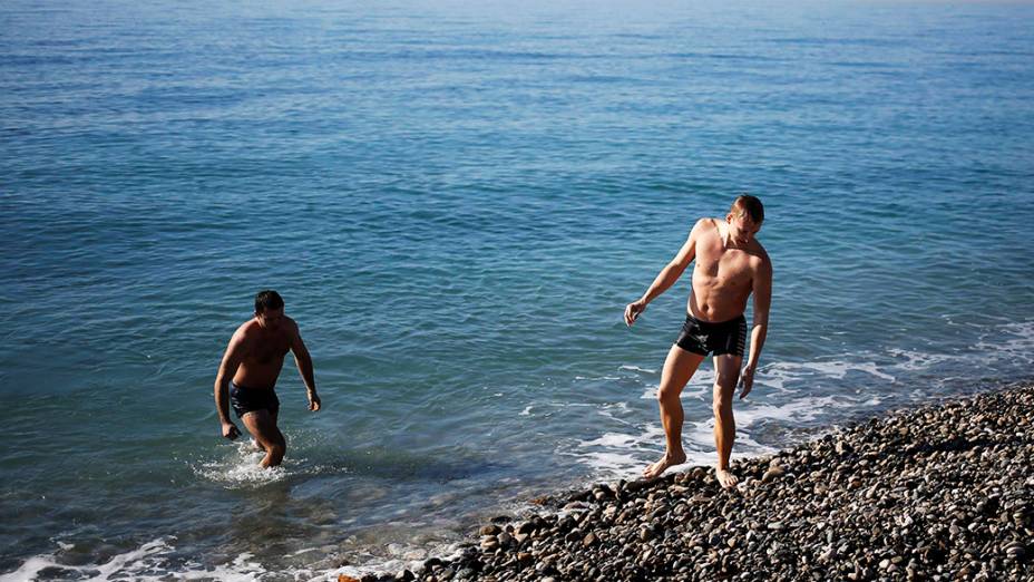 Moradores aproveitam o bom tempo para ir à praia, no Mar Negro, nas proximidades do Parque Olímpico em Sochi, durante os Jogos de Inverno