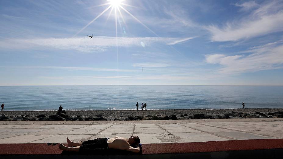 Homem toma banho de sol nas proximidades do Parque Olímpico em Sochi, durante os Jogos de Inverno