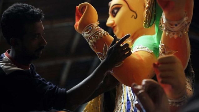 Artista retoca estátua do deus hindu Durga, que simboliza poder e o triunfo do bem sobre o mal, em Siliguri, Índia