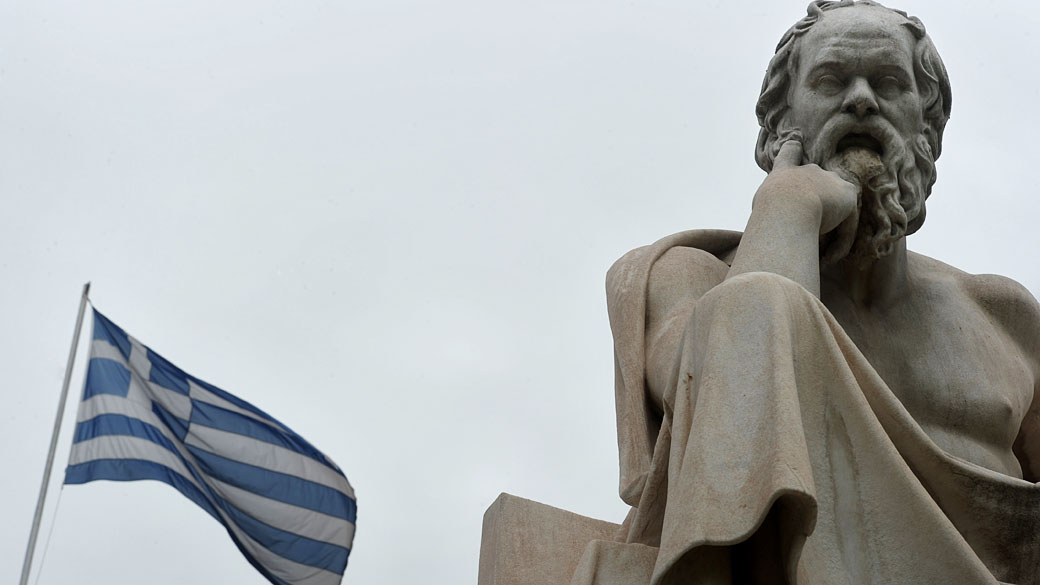 Bandeira grega ao lado de uma estátua do filósofo grego Sócrates, no centro de Atenas