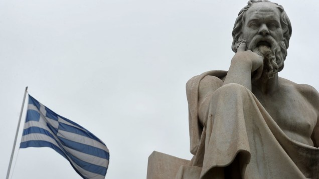 Bandeira grega ao lado de uma estátua do filósofo grego Sócrates, no centro de Atenas