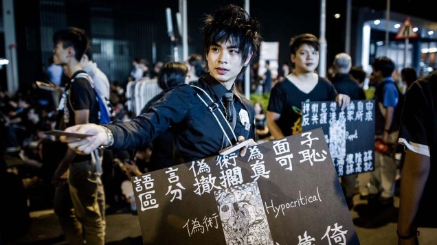 Em Hong Kong, estudante distribui folhetos pedindo a retirada completa dos planos do governo para implementação de aulas de patriotismo chinês