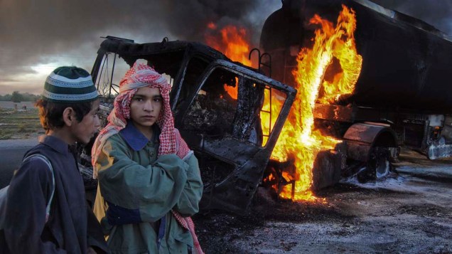 Estudantes perto de caminhões de combustível incendiados por rebeldes em Bolan, Paquistão