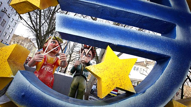 Em desfile de Carnaval alemão, bonecos que representam as agências de rating "Fitch" e "Poors" miram o símbolo do euro