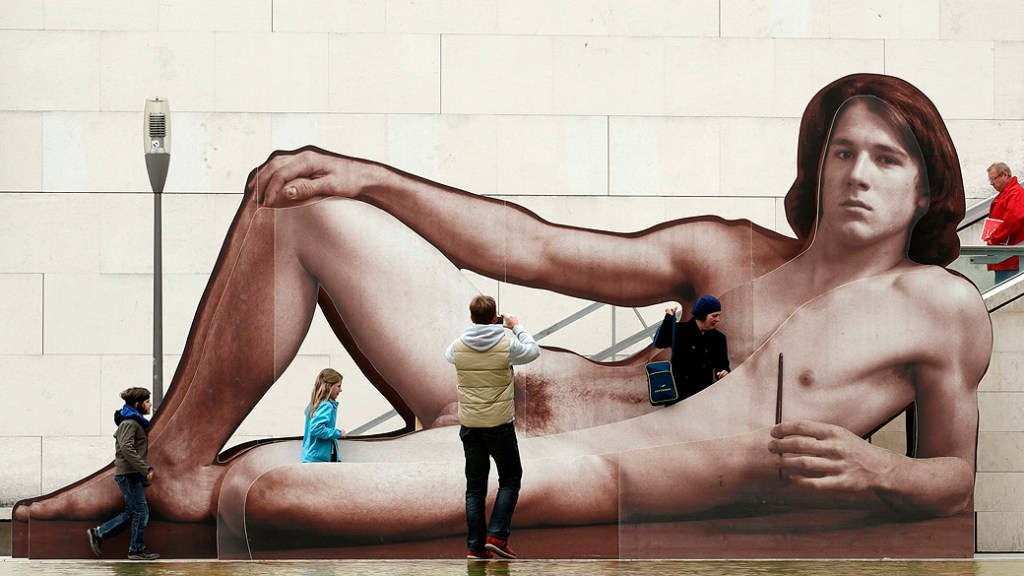 Pessoas fotografam o anúncio da exibição 'Naked men', um enorme retrato montado em uma escada em frente ao Leopold Museum em Viena, na Áustria