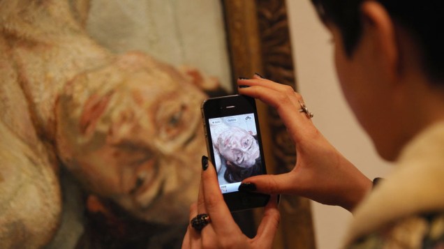 Mulher usa celular para fotografar a obra "Naked Portrait" do artista Lucian Freud, em exposição no National Portrait Gallery em Londres