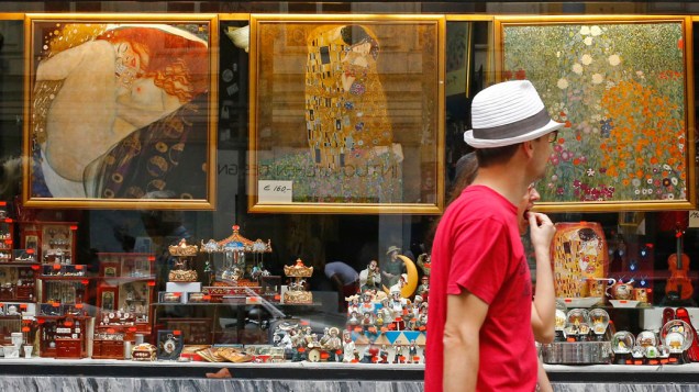 Homem olha para a vitrine de uma loja de souvenirs com réplicas de pinturas do artista austríaco Gustav Klimt em Viena, Áustria