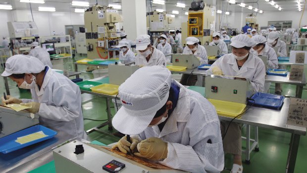 Funcionários em linha de montagem da BYD, na China, instalando chips em placas eletrônicas