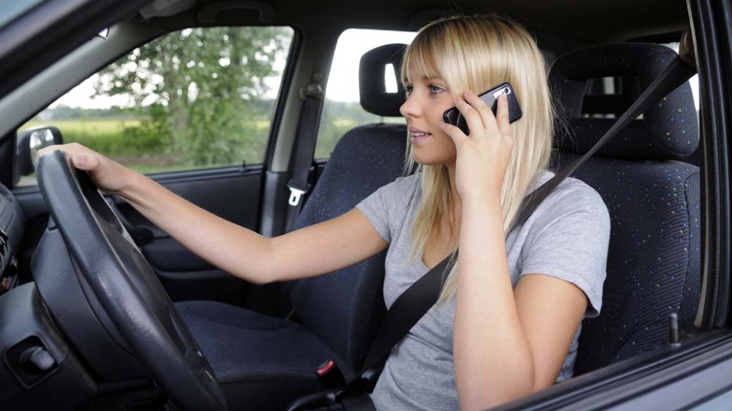 Mulher falando ao celular enquanto dirige