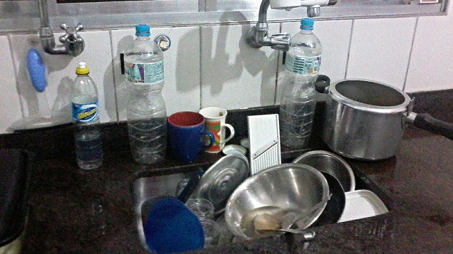 Allan Bezerra acumula panelas, pratos e copos na pia para lavar no dia seguinte, quando a água volta a correr pela torneira