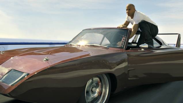 Não satisfeito em ficar sentado ao volante de seu Daytona 1969, Toretto faz pose pendurado na porta do carro