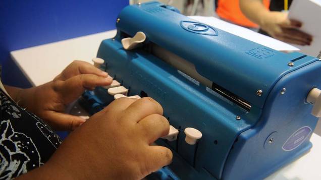 Pessoa com deficiência visual digita em máquina de escrever que utiliza o método Braille