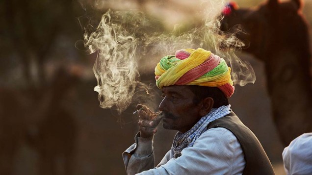 Negociante fuma cigarro indiano, Bidi, durante feira de camelos em Pushkar