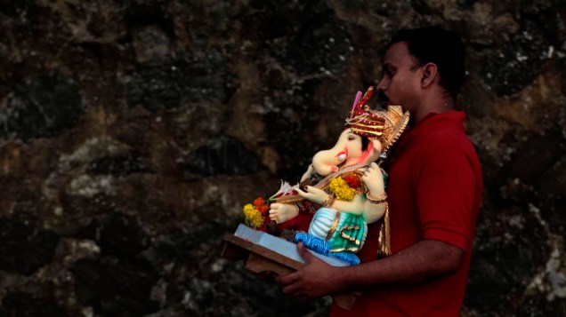 Indiano carrega imagem do deus Ganesha durante as festividades do Ganesh Chaturthi, que celebra o nascimento do deus