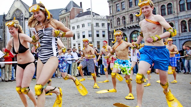 Pessoas vestidas com equipamentos de mergulho amarelos participam da Corrida Nacional Flipper, na praça Dam, em Amsterdã, na Holanda
