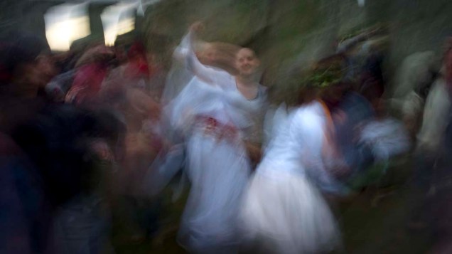 Foliões dançam ao nascer do sol no solstício de inverno, dia mais curto do ano, no Stonehenge em Salisbury, Reino Unido