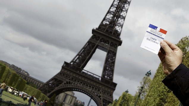 Homem apresenta o seu cartão eleitoral em frente à Torre Eiffel, quatro dias antes das eleições, na França