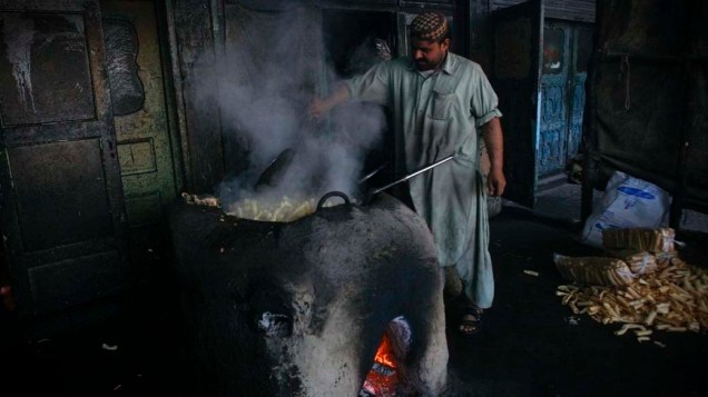 Homem frita biscoitos em loja na cidade de Quetta, Paquistão