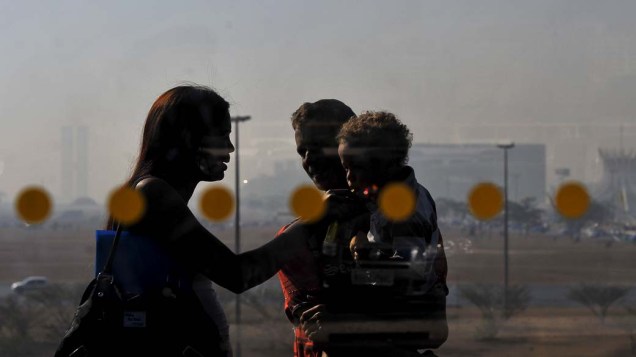 Família durante dia seco em Brasília, com a cidade coberta por nuvens de fumaça causada por focos de incêndio em áreas próximas à capital