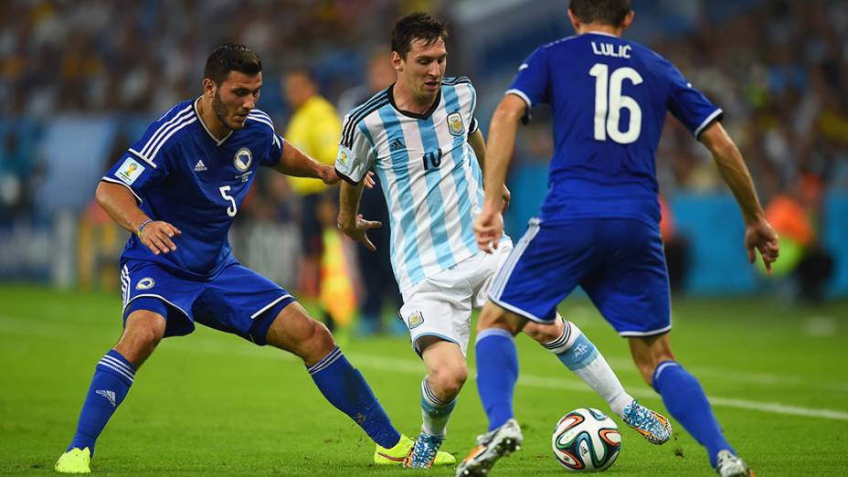 O argentino Lionel Messi dribla dois jogadores da Bósnia no Maracanã, no Rio