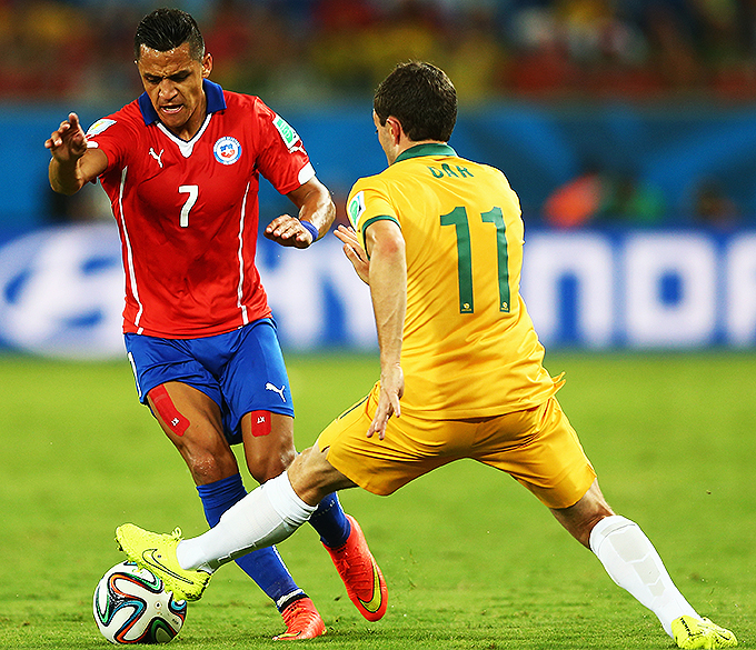 Tommy Oar, da Australia, marca o chileno Alexis Sanchez, na Arena Pantanal em Cuiabá