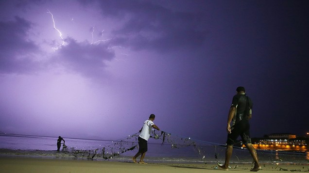 Pescadores recolhem suas redes na praia de Copacabana, antes de uma tempestade