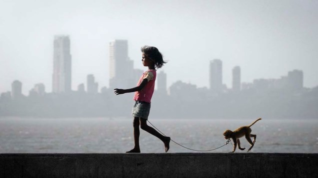 Garota passeia com seu macaco de estimação em Mumbai, Índia