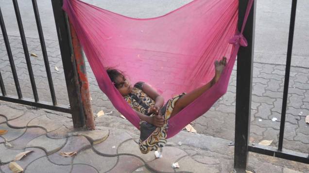 Garota indiana dorme às margens de uma rodovia na cidade de Mumbai