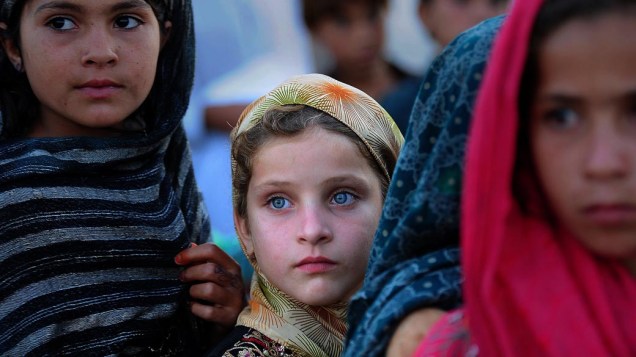 Crianças de famílias que fugiram de suas casas, temendo ataques violentos entre o exército e militantes islâmicos, aguardam em fila por distribuição de alimentos em Jalozai, no Paquistão