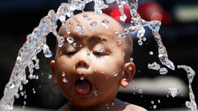 Menino se refresca com água de mangueira em Manila, nas Filipinas