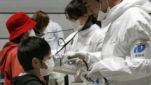 Profissionais de saúde monitoram níveis de radiação em garoto em Fukushima