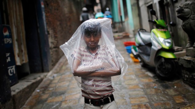 Garoto se protege da chuva em Katmandu, no Nepal