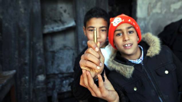 Crianças mostram munição nos escombros de uma delegacia queimada durante protestos na cidade de Kef, Tunísia