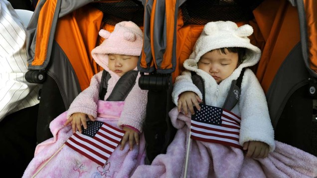 Gêmeas durante cerimônia em que 125 cidadãos serão naturalizados americanos em comemoração aos 125 anos da estátua da liberdade em Nova York, nos Estados Unidos