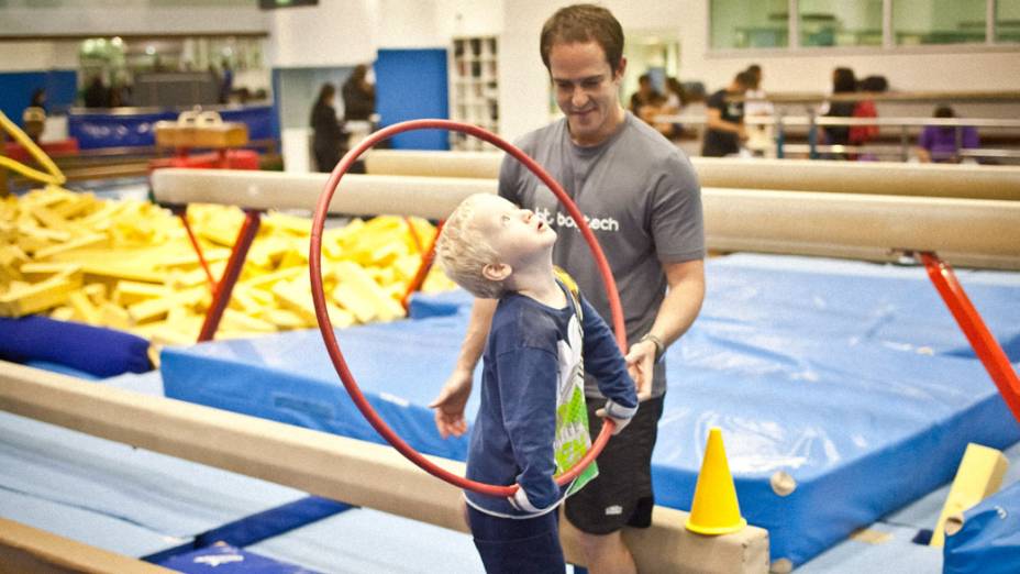 Ginástica para autistas: Gustavo passa o bambolê por cima e por baixo enquanto anda