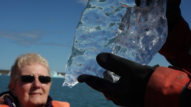 Turista observa pedaço de iceberg da Glacier Lagoon