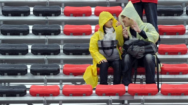 Espectadores protegem-se da chuva forte antes do início do Grande Prêmio da Coréia do Sul. 24/10/2010